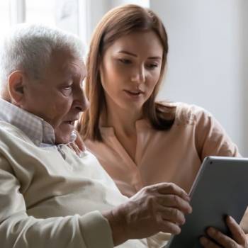 Une femme montre une tablette à son père âgé